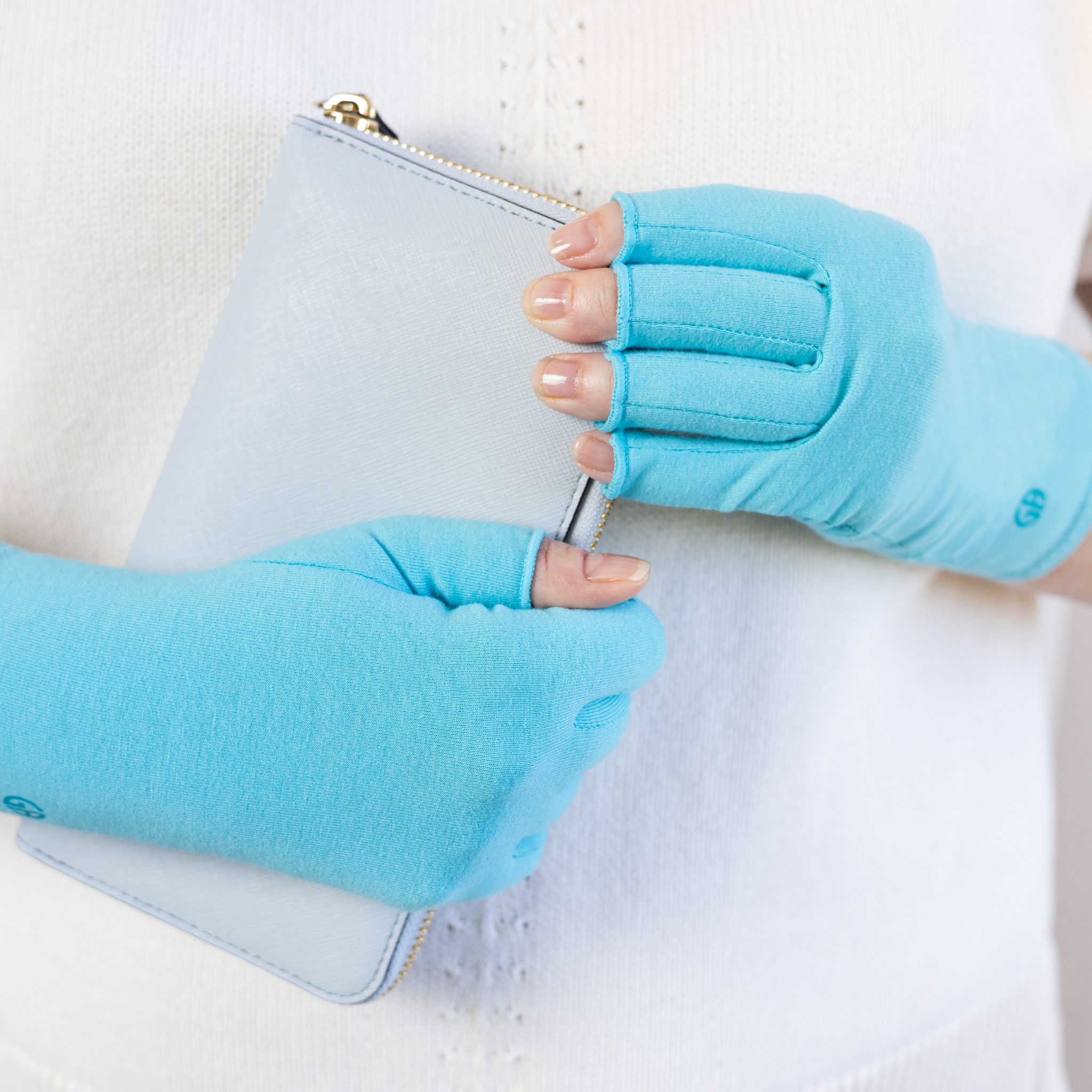 Grace and Able compression gloves in aqua blue, shown being used to grip a purse